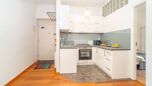A compact kitchen with white cabinets, a built-in oven, and a grey countertop.
