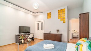A modern bedroom with a bed, a desk, a TV, and a wardrobe.