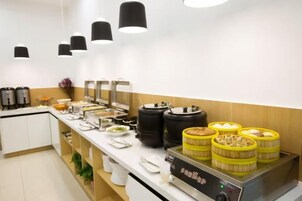 Montaje de bufé con diferentes recipientes de comida, una estación de café y un dispensador de agua.