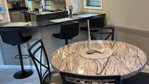 A modern kitchen with a central island, bar stools, and a round marble table. - Home away from home (Indiana)