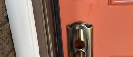 A door with a black electronic keypad lock and a traditional keyhole lock.