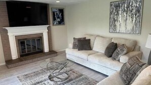 A living room with a fireplace, a sofa, a coffee table, and a TV. - Home away from home (Indiana)