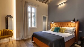 A bedroom with a large bed, a chair, a mirror, and a window with curtains. - Gorgeous apartment with city views! Up to 8! (Firenze)