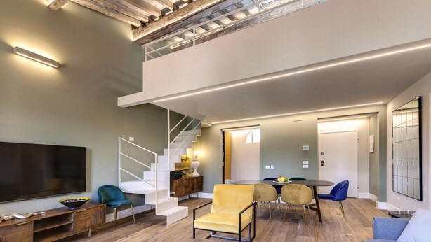 A spacious living area with a modern staircase, a flat-screen TV, and a dining table with chairs. - Gorgeous apartment with city views! Up to 8! (Firenze)