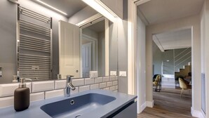 A modern bathroom with a large mirror, a blue sink, and a chrome towel rack. - Gorgeous apartment with city views! Up to 8! (Firenze)