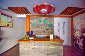 A reception desk with a wooden counter and a brick wall backdrop. - Xi'an Inn (Zhangjiajie Zixia Temple) (Zhangjiajie)