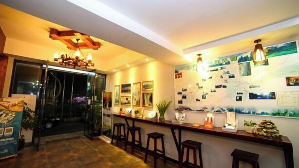 A bar area with wooden stools, a counter with various items, and a wall decorated with pictures and notes. - Xi'an Inn (Zhangjiajie Zixia Temple) (Zhangjiajie)