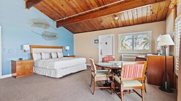 A bedroom with a bed, dresser, bedside tables, lamp, and a dining area with chairs and a table.