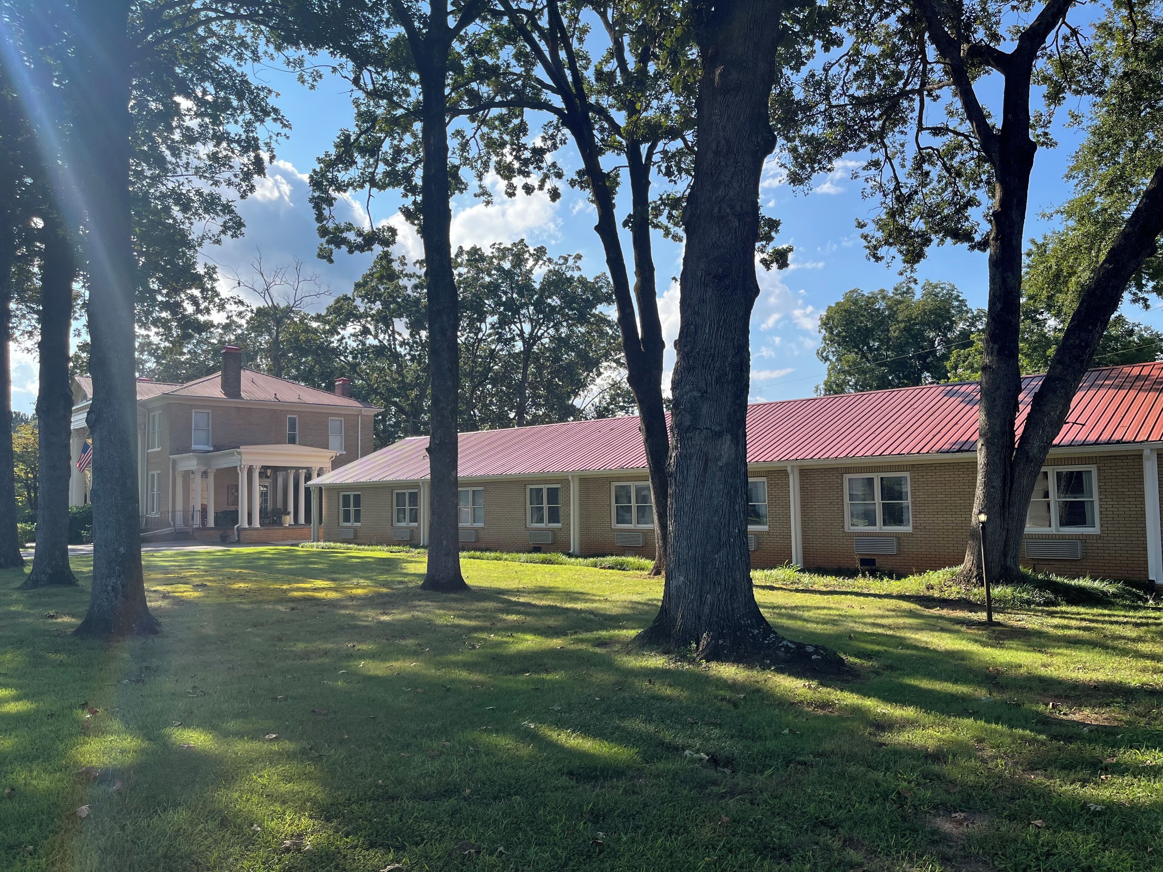 A building with a red roof, surrounded by trees and grass.