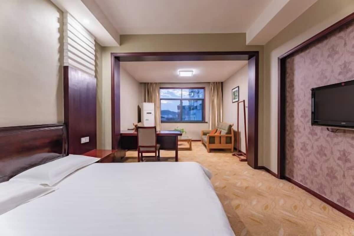 Ein Hotelzimmer mit Bett, Schreibtisch, Stuhl, Fernseher und einem Fenster mit Blick.
