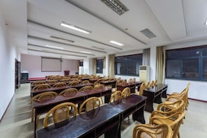 A conference room with long tables and chairs, a projector screen, and a large window. - Jindu Hotel (Wuyuan)