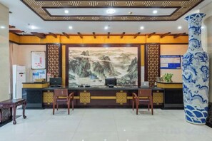 A reception desk with a large painting, a vase, and a bulletin board. - Jindu Hotel (Wuyuan)