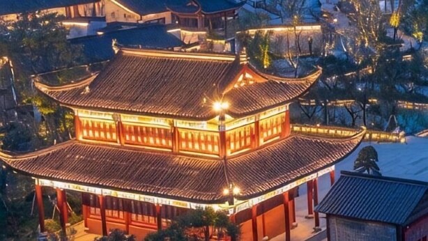 A traditional building with multiple levels and a tiled roof, surrounded by trees and a snow-covered ground. - Jindu Hotel (Wuyuan)