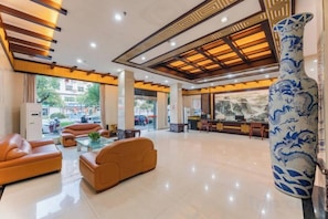 A spacious lobby with leather sofas, a large decorative vase, and a reception desk. - Jindu Hotel (Wuyuan)