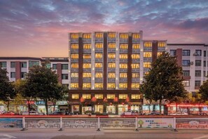 A multi-story hotel with a modern facade, large windows, and a well-lit entrance. - Jindu Hotel (Wuyuan)