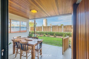 An outdoor patio with a wooden table and chairs, a view of the backyard, and a fence. - 2 Suite Apartment in Condo With Pool Eko0008 (Camaçari)