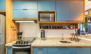 A modern kitchen with blue cabinets, a built-in microwave, and a gas stove. - 2 Suite Apartment in Condo With Pool Eko0008 (Camaçari)