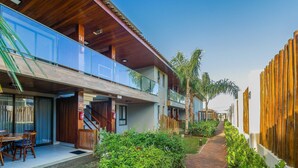 Un bâtiment moderne doté d’une façade en bois, d’un balcon en verre et d’un chemin bordé de verdure.
