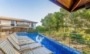 A modern pool area with lounge chairs and a wooden deck, surrounded by a wooden fence and trees. - 2 Suite Apartment in Condo With Pool Eko0008 (Camaçari)