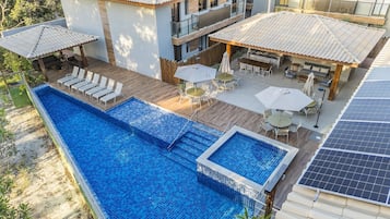 Piscina no terraço com deck de madeira, área de estar externa e painéis solares.