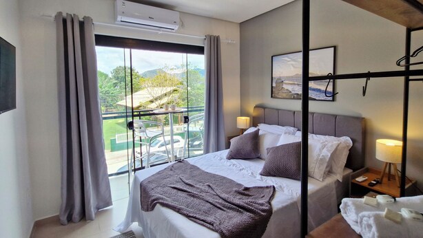 Une chambre d’hôtel avec un lit, une télévision, un balcon avec vue et un tableau au mur.