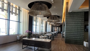 A modern restaurant with long tables, pendant lighting, and large windows.
