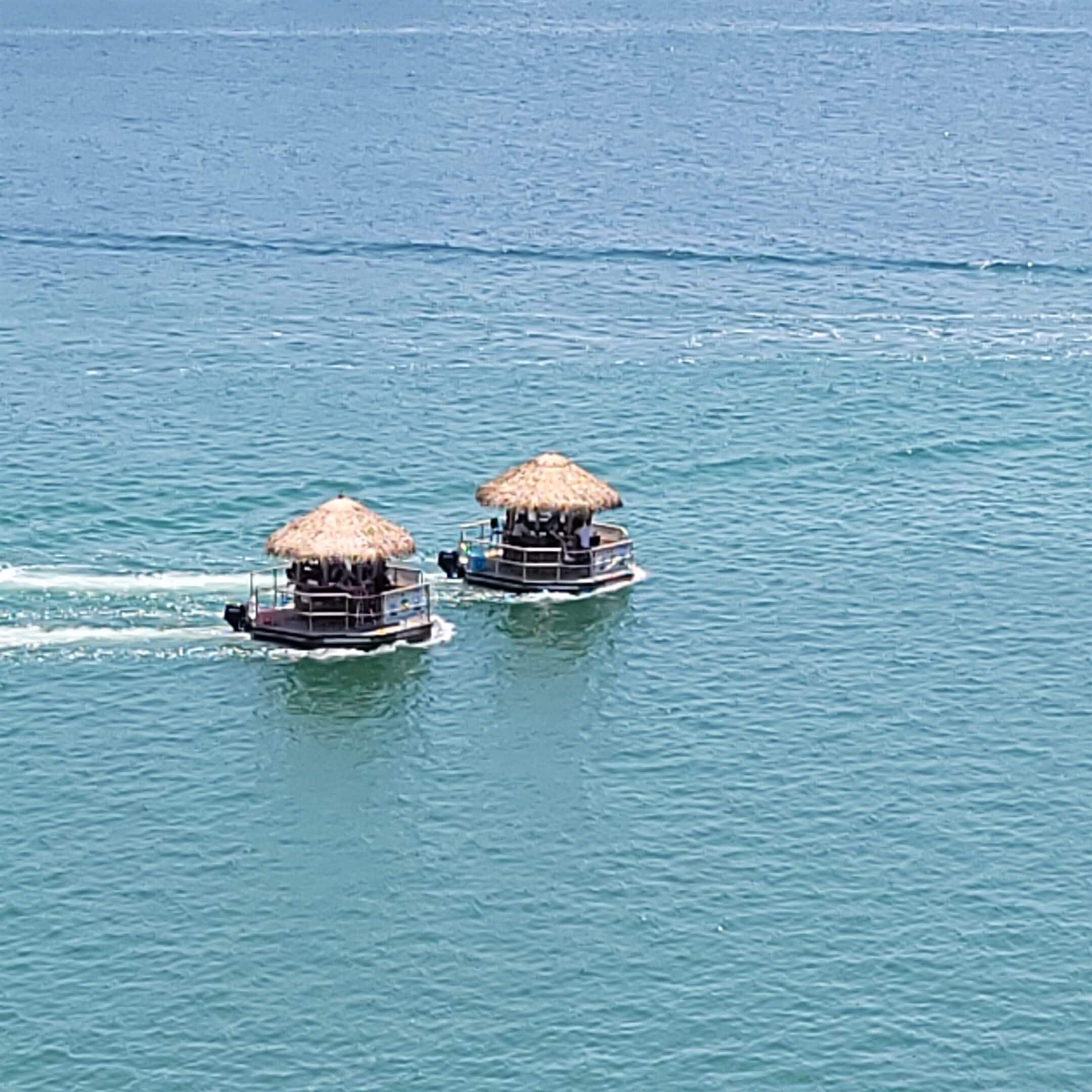 Dos estructuras flotantes con techos de paja sobre aguas tranquilas.