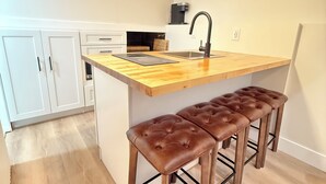 Een moderne keuken met een houten aanrecht, een spoelbak en twee barkrukken.