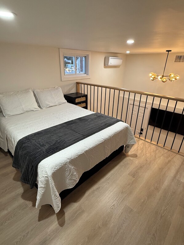 A bedroom with a bed, a nightstand, a window, and a ceiling light fixture.