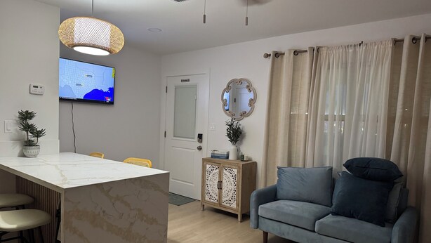 Un salon moderne avec un îlot en marbre, un canapé bleu, un meuble en bois et un téléviseur fixé au mur.