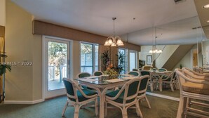 A dining area with a glass table, wicker chairs, and a chandelier.
