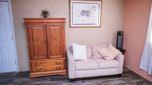 Et værelse med en beige sofa, et træskab og et billede i ramme på væggen.