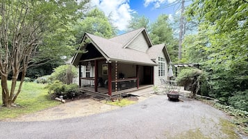 Een chalet met veranda, omringd door bomen.