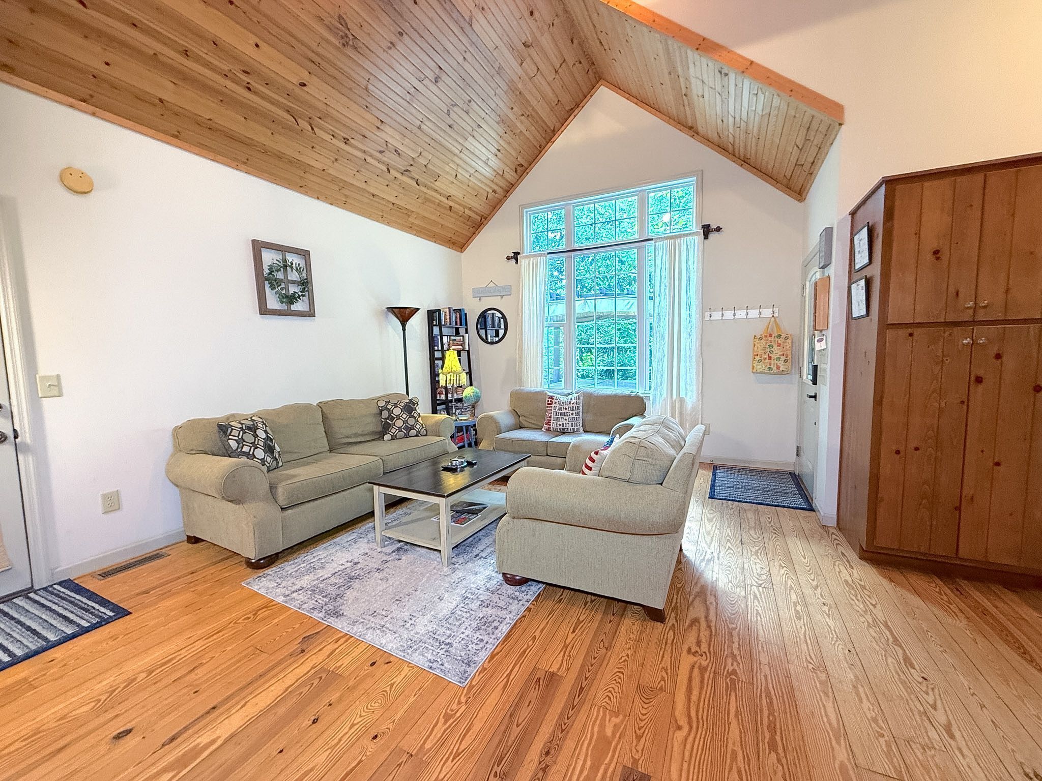 Un salon spacieux avec un haut plafond, un plancher en bois et une grande fenêtre qui laisse entrer la lumière naturelle.