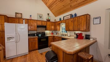 A kitchen with wooden cabinets, a white refrigerator, a stove, and a tiled island.