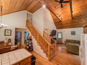 A spacious living area with a wooden staircase, a dining table, and a sofa.