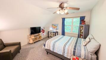 A bedroom with a bed, a TV, a ceiling fan, a window with curtains, and a bookshelf.