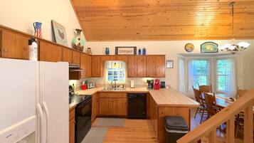 A kitchen with wooden cabinets, a refrigerator, a sink, and a dining area with chairs.