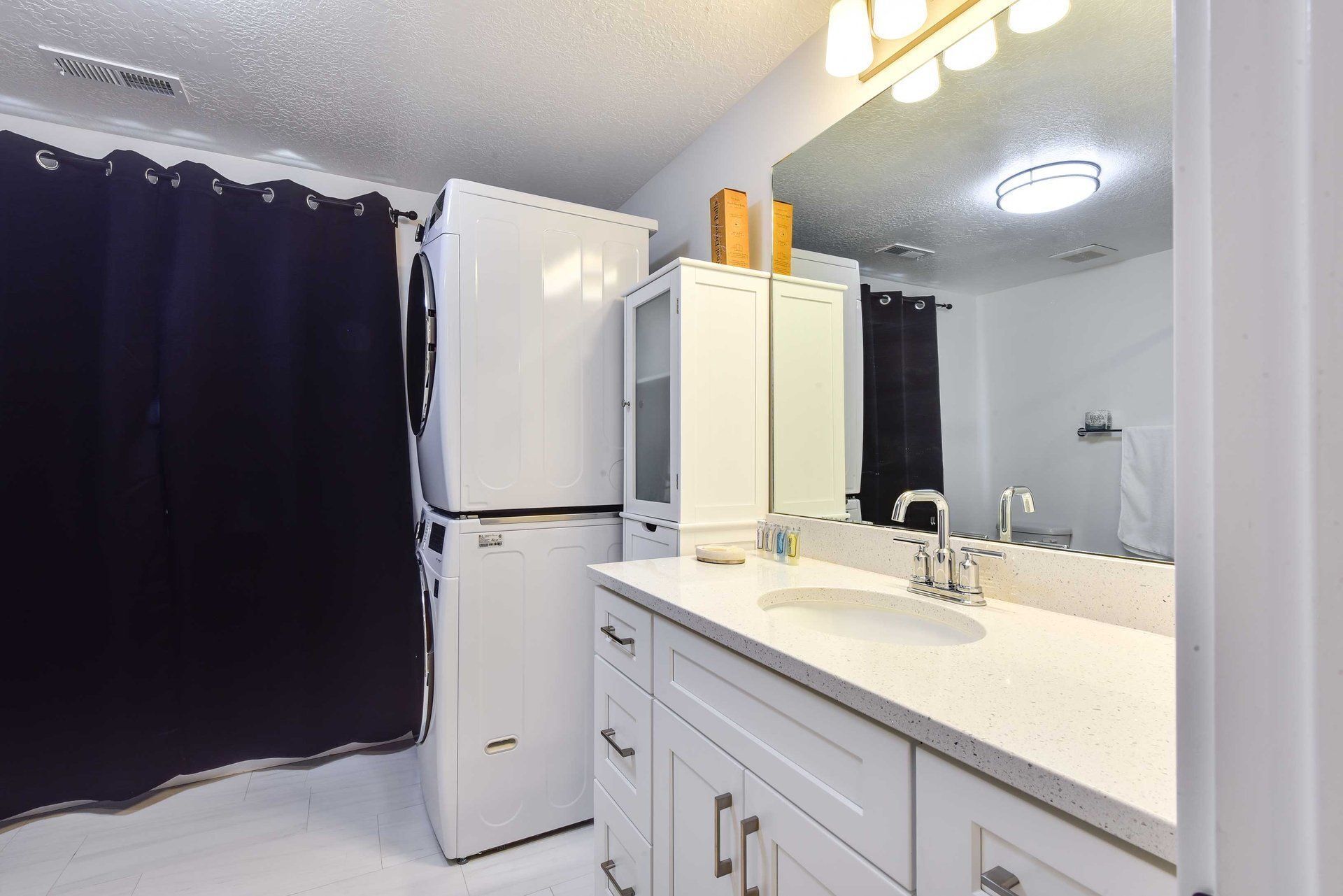 Un baño pequeño con un lavabo blanco, un espejo y una lavadora blanca.