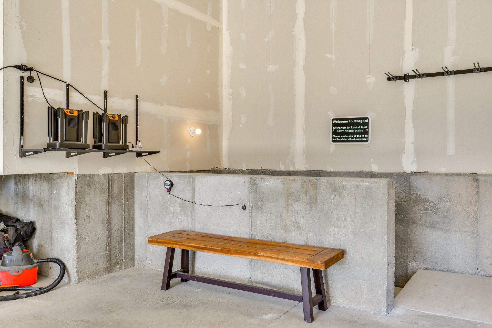 A room with a concrete bench, a power tool station, and a sign indicating a rental unit entrance.