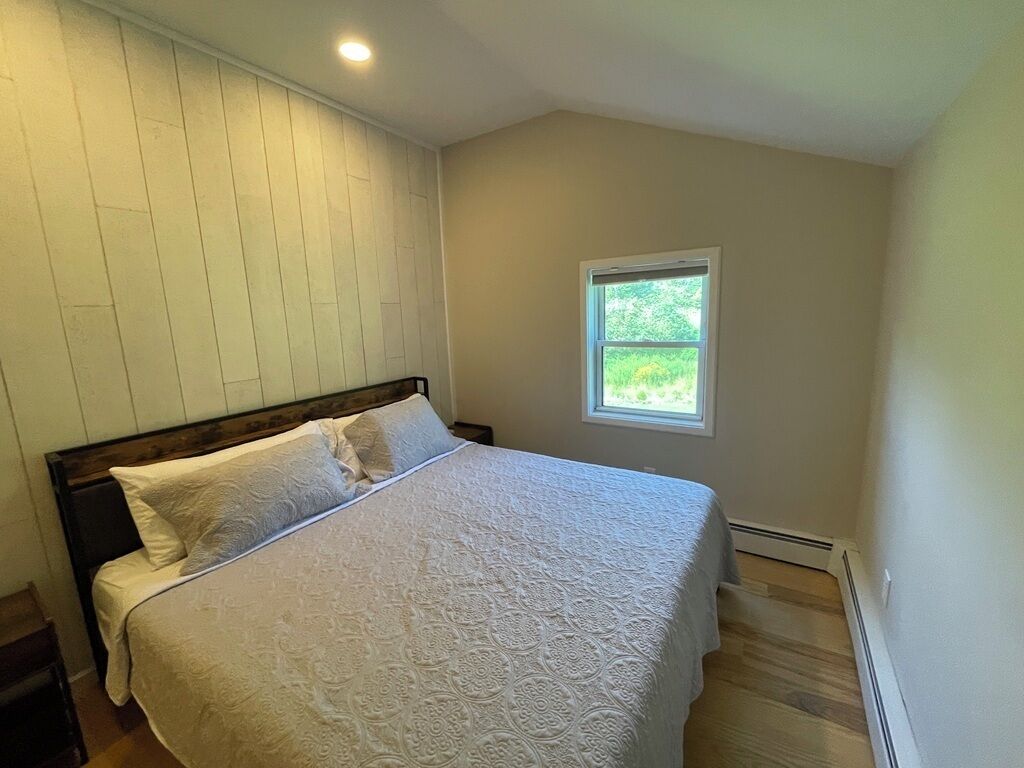 Une chambre à coucher avec un lit, une fenêtre et un mur en bois.