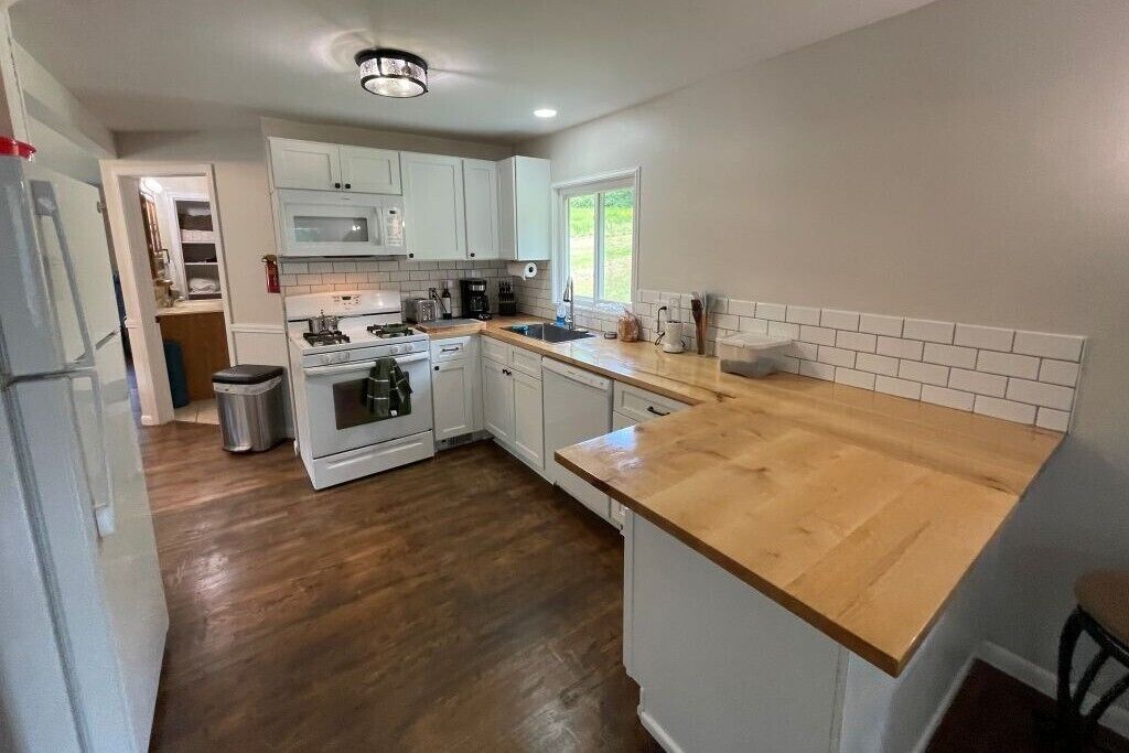 A kitchen with white cabinets, a wooden countertop, and a stainless steel sink.