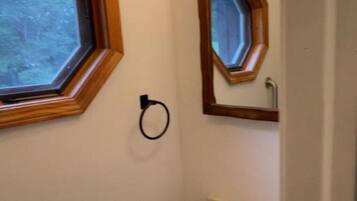 A bathroom with a hexagonal window, a sink, and a mirror with a wooden frame.