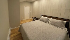 A bedroom with a large bed, a wooden headboard, and a white wall paneling.