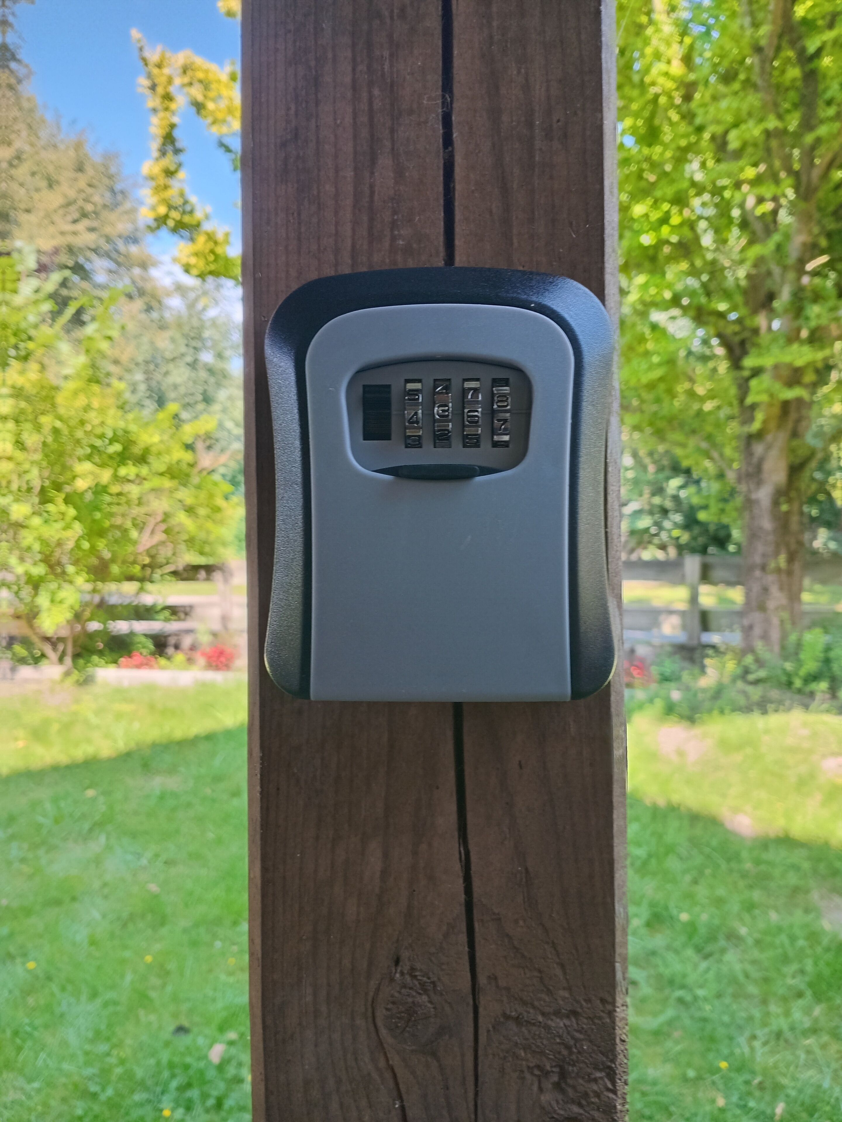 A keypad lock on a wooden post.