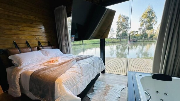 Une chambre avec un lit, une télévision, une grande fenêtre et un jacuzzi.