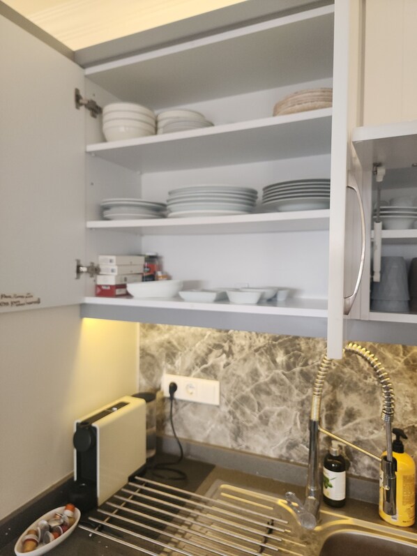 Una cocina con armarios blancos, salpicadero de mármol y un lavamanos con dispensador de jabón amarillo.