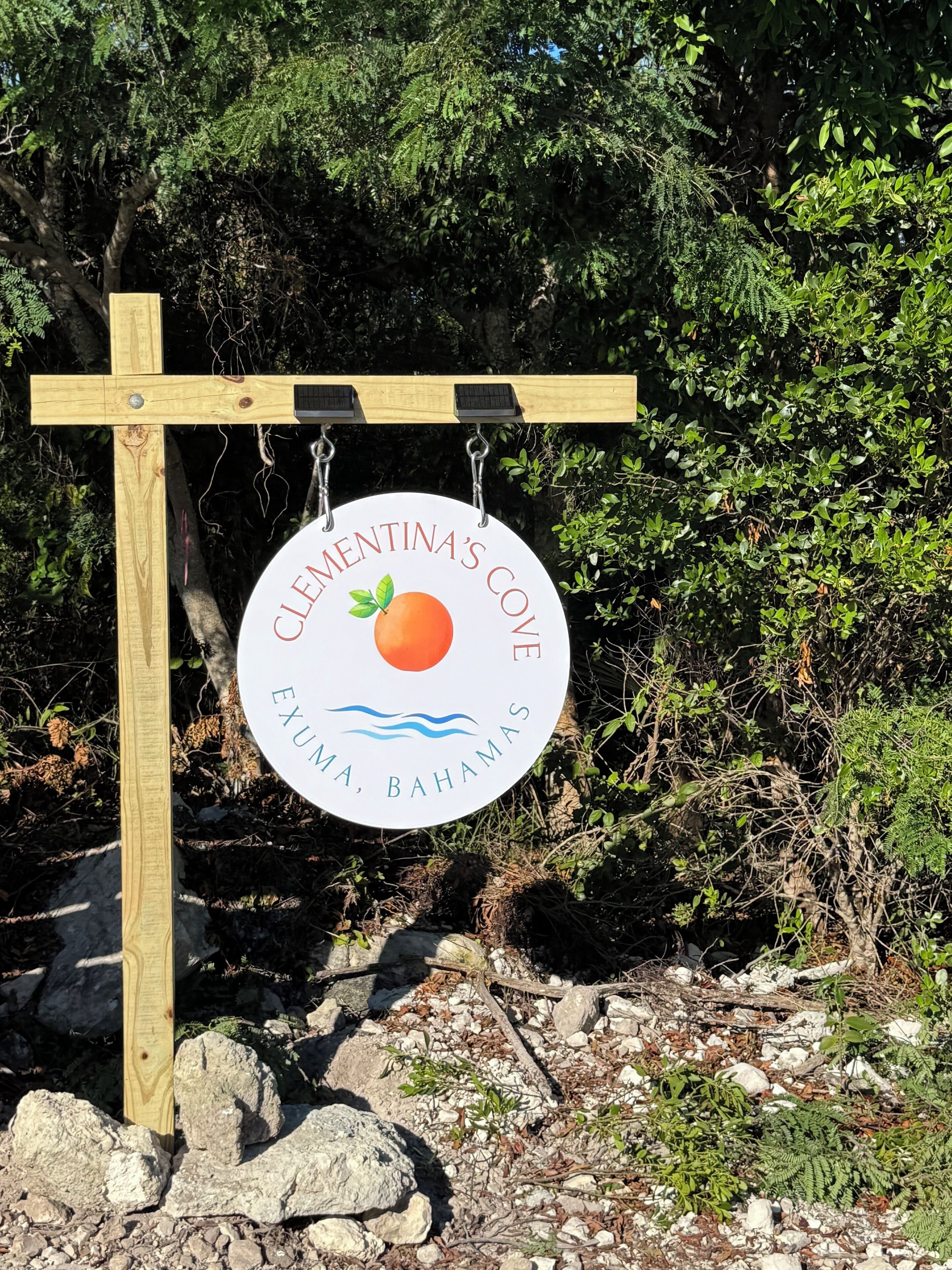 A wooden sign with a circular logo for Clementina's Cove in Exuma, Bahamas.