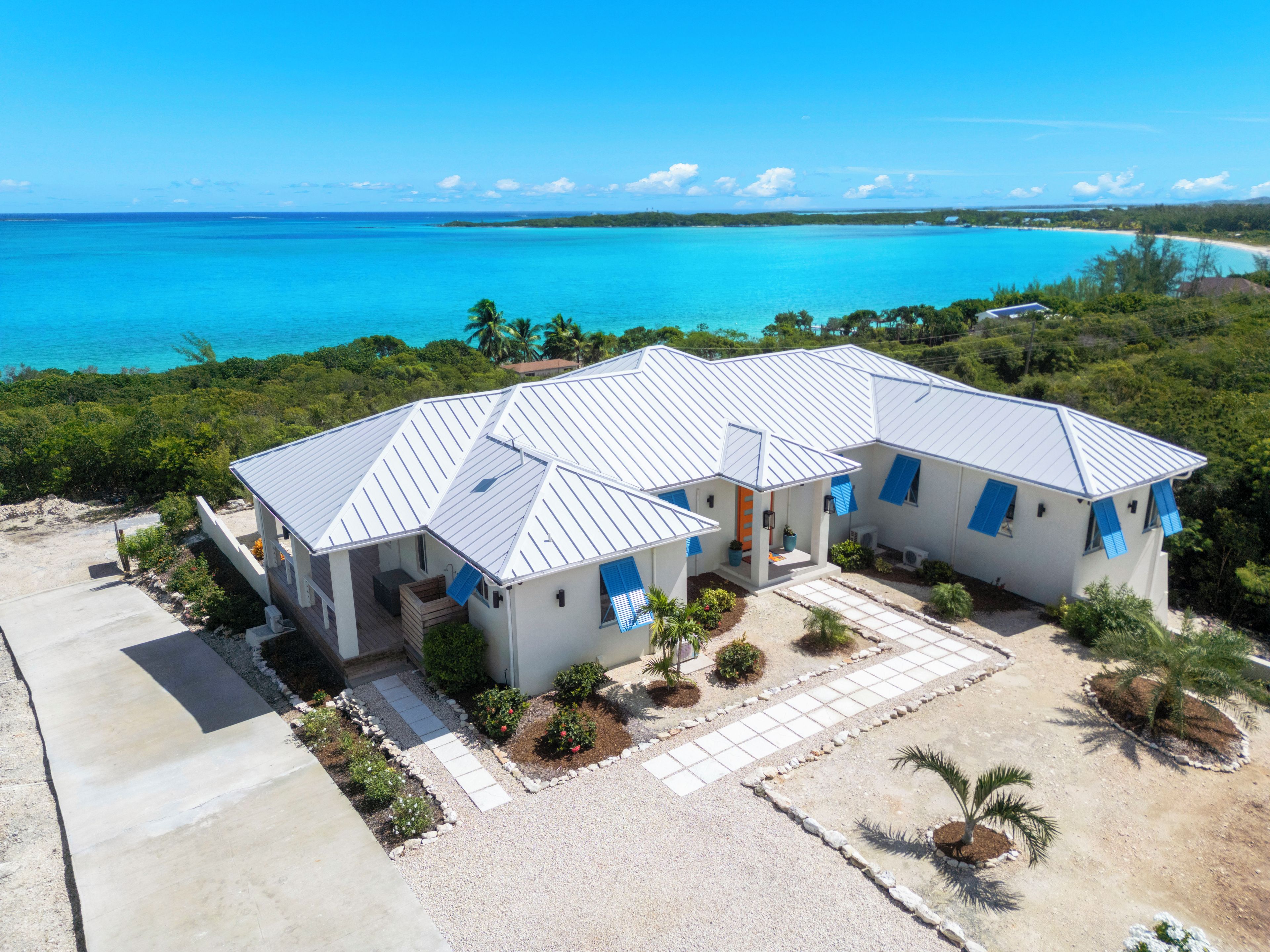 A beachfront property with a two-story house, a covered patio, and a view of the ocean.
