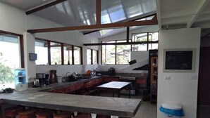 Una cocina amplia con una isla grande, taburetes de bar y vistas a través de las ventanas.